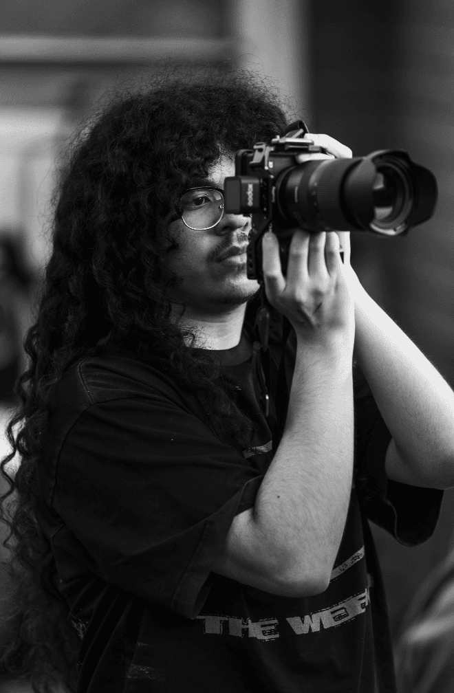 Joseth, a young photographer, holds up a camera in the crowd during a live performance